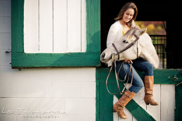 Girl sitting on stall door holding her horse. Annapolis Kent Island Maryland High School Senior Portrait Photography with Horse Pet by photographer Leo Dj