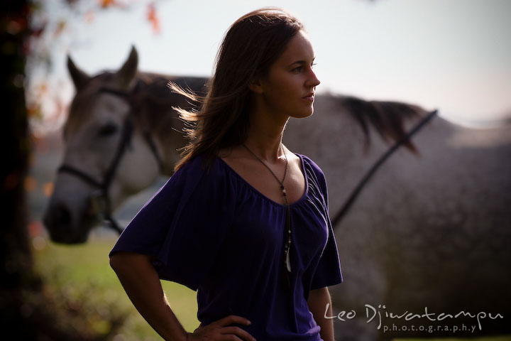 Girl posing for camera while her mare is in the background