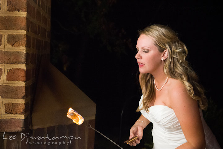 Bride looking at marshmallow roasting with fire. Mariott Aspen Wye River Conference Center Wedding photos at Queenstown Eastern Shore Maryland, by photographers of Leo Dj Photography.