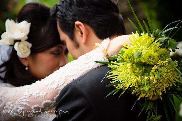 bride and groom cuddling, holding flower bouquet