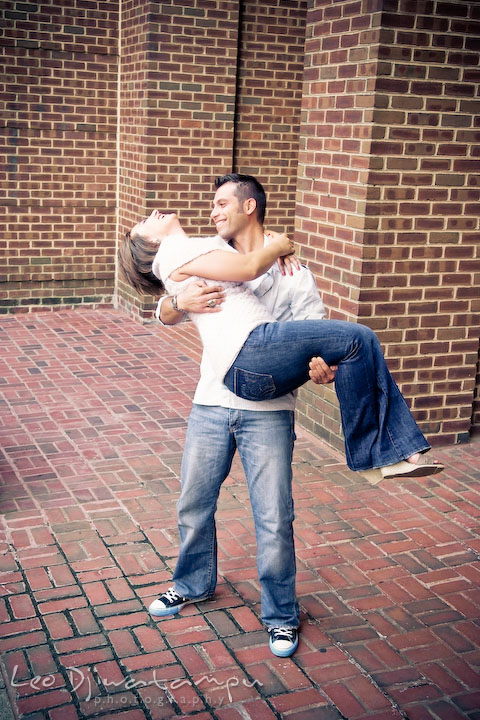 Engaged guy lift up his fiancee, laughing. Candid Old Town Alexandria Virginia Engagement Photography Session by Wedding Photographer Leo Dj