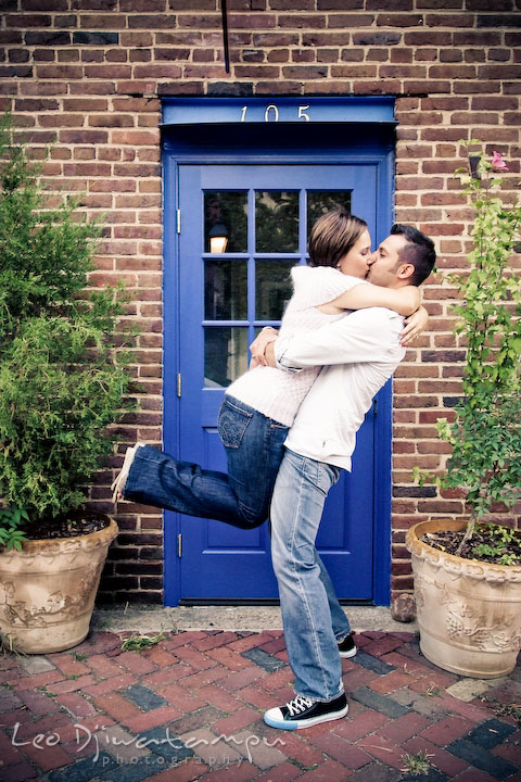 Engaged guy lifted up his fiance and kissed by a blue door. Candid Old Town Alexandria Virginia Engagement Photography Session by Wedding Photographer Leo Dj