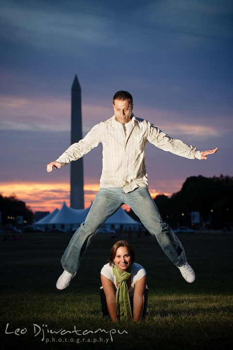 Engaged guy jumped over his fiancee that is kneeling on the ground. Washington DC, Smithsonian, The Mall Pre-wedding Engagement Session Photographer Leo Dj Photography