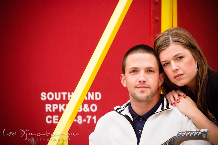 Engaged girl and her fiancé posing in front of a red caboose. Pre-Wedding Engagement Photo Session at Sykesville Maryland with Train Rail and Caboose by wedding photographer Leo Dj Photography