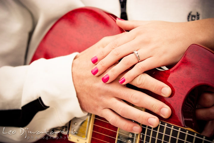 Engaged guy and girl showing of their diamond engagement ring with a red electric guitar. Pre-Wedding Engagement Photo Session at Sykesville Maryland with Train Rail and Caboose by wedding photographer Leo Dj Photography