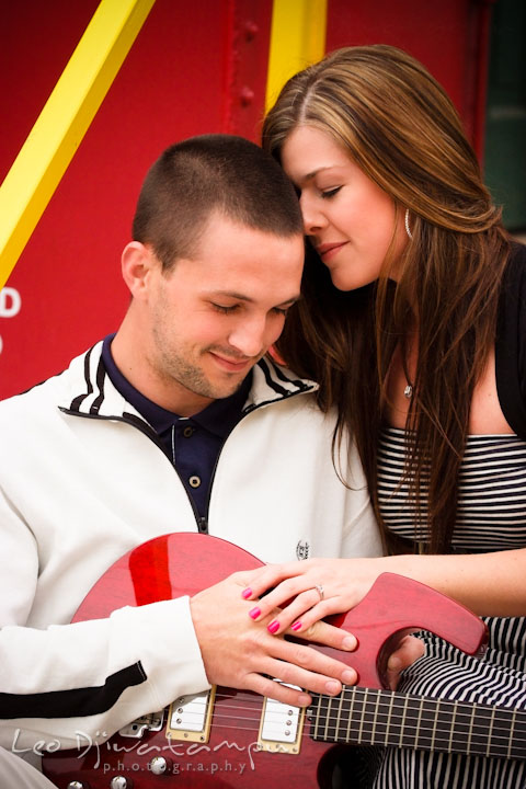 Engaged couple cuddling by a red caboose. Pre-Wedding Engagement Photo Session at Sykesville Maryland with Train Rail and Caboose by wedding photographer Leo Dj Photography