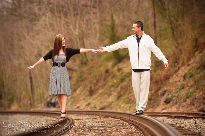 Engaged guy and girl walking on rail tracks. Pre-Wedding Engagement Photo Session at Sykesville Maryland with Train Rail and Caboose by wedding photographer Leo Dj Photography