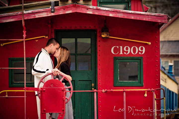 Engaged guy and girl kissing in a red caboose. Pre-Wedding Engagement Photo Session at Sykesville Maryland with Train Rail and Caboose by wedding photographer Leo Dj Photography