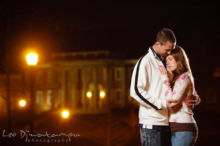 Engaged guy and girl cuddling in the evening by the building and street lights. Pre-Wedding Engagement Photo Session at Sykesville Maryland with Train Rail and Caboose by wedding photographer Leo Dj Photography