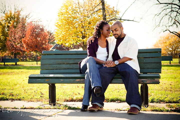 romantic couple sitting on bench holding hand. Federal Hill Park Baltimore pre-wedding engagement portrait
