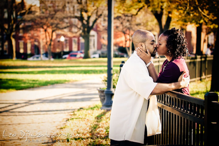 engaged couple kissing by the fence. Federal Hill Park Baltimore pre-wedding engagement portrait