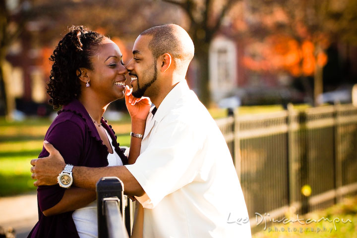 engaged couple smiling and laughing by the fence. Federal Hill Park Baltimore pre-wedding engagement portrait