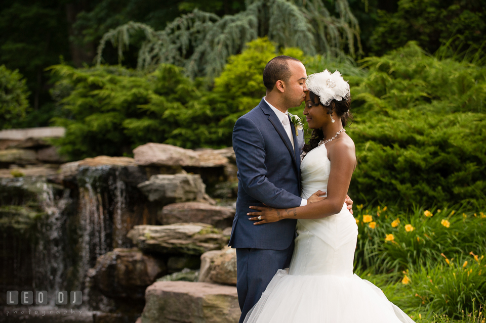 Groom kissed Bride on forehead by the outdoor rock garden with waterfall. Falls Church Virginia 2941 Restaurant wedding ceremony and reception photo, by wedding photographers of Leo Dj Photography. http://leodjphoto.com