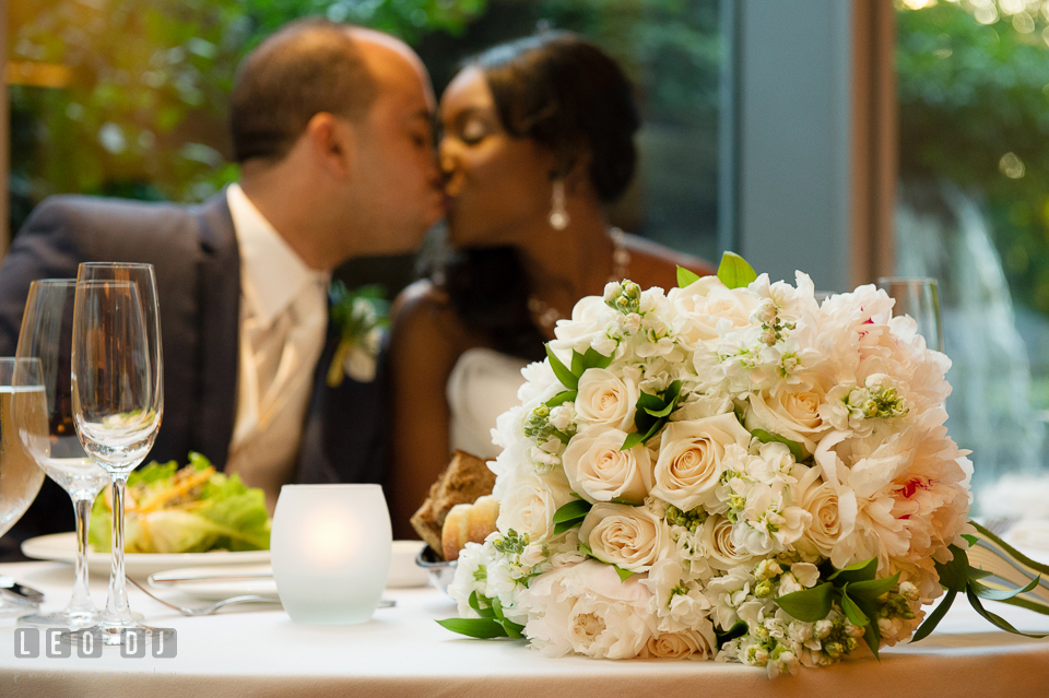 Bride and Groom kissed behind the sweetheart table with the large pink rose and white peonies floral bouquet by florist Highway to Hill. Falls Church Virginia 2941 Restaurant wedding ceremony and reception photo, by wedding photographers of Leo Dj Photography. http://leodjphoto.com