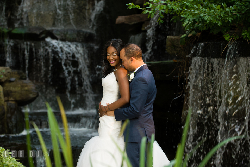 Bride and Groom cuddling by the tall waterfall. Falls Church Virginia 2941 Restaurant wedding ceremony and reception photo, by wedding photographers of Leo Dj Photography. http://leodjphoto.com