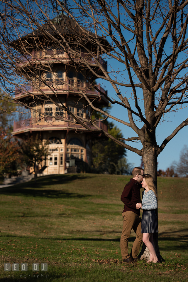 Patterson Park Baltimore Maryland engaged man kissing fiancée by tree photo by Leo Dj Photography.