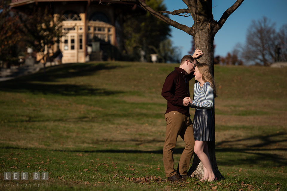 Patterson Park Baltimore Maryland engaged man laughing with fiancee by tree photo by Leo Dj Photography.