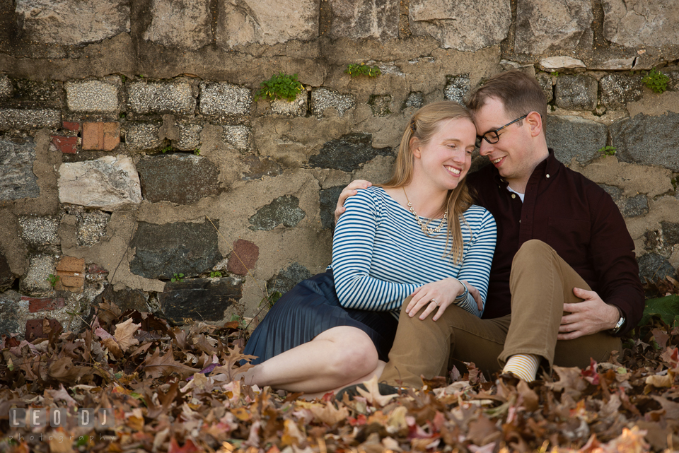 Patterson Park Baltimore Maryland engaged couple cuddling by autumn leaves photo by Leo Dj Photography.