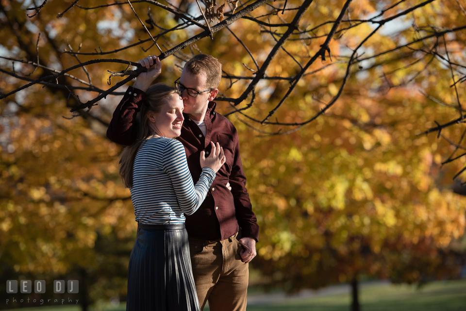 Patterson Park Baltimore Maryland engaged girl by autumn leaves kissed by fiance photo by Leo Dj Photography.