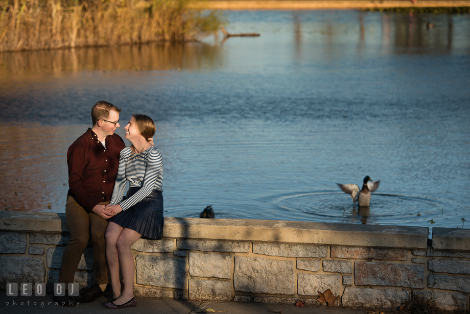 Patterson Park Baltimore Maryland engaged couple sitting by a pond laughing photo by Leo Dj Photography.