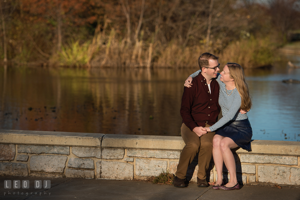 Patterson Park Baltimore Maryland engaged man cuddling with fiancee by pond photo by Leo Dj Photography.