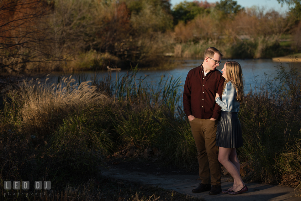 Patterson Park Baltimore Maryland engaged snuggled with fiance by a pond photo by Leo Dj Photography.