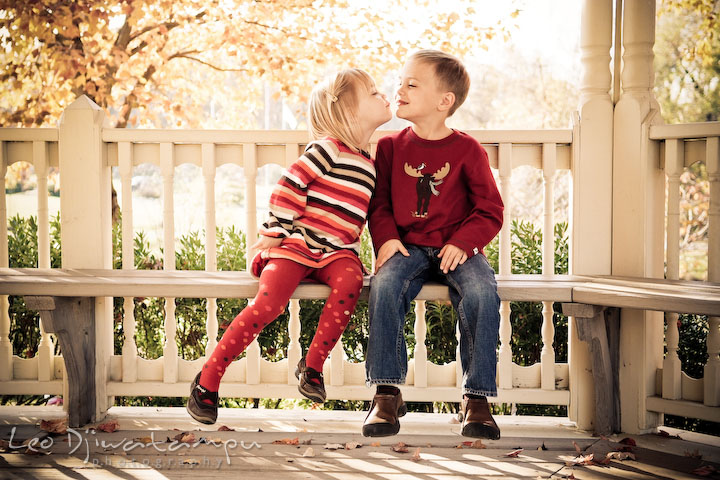 sister kissing smiling brother on bench. Fun candid family children lifestyle photographer Annapolis Maryland