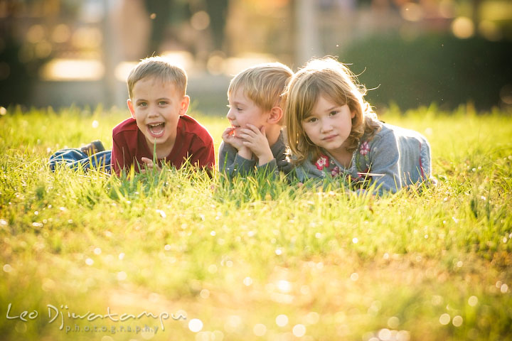 boy girl. brother, sister and cousin laying on the grass. Fun candid family children lifestyle photographer Annapolis Maryland