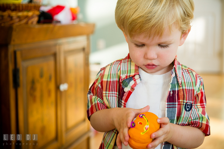 Little boy playing with a little pumpkin decoration. Queenstown, Eastern Shore Maryland candid children and family lifestyle portrait photo session by photographers of Leo Dj Photography. http://leodjphoto.com