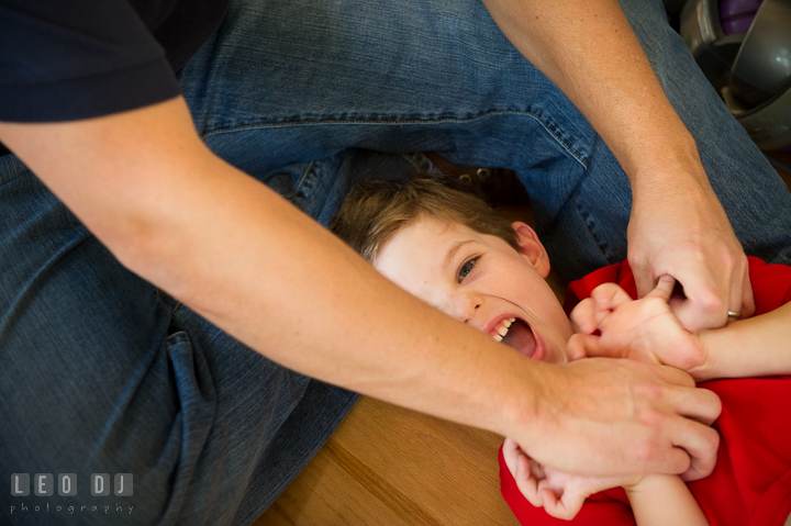 Toddler boy on the floor laughing as Father tickles him. Queenstown, Eastern Shore Maryland candid children and family lifestyle portrait photo session by photographers of Leo Dj Photography. http://leodjphoto.com