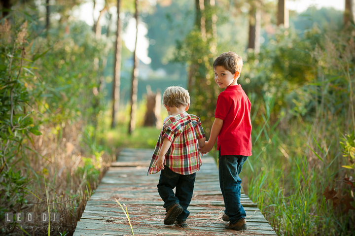 Big brother looking back as he walks with his little brother. Queenstown, Eastern Shore Maryland candid children and family lifestyle portrait photo session by photographers of Leo Dj Photography. http://leodjphoto.com