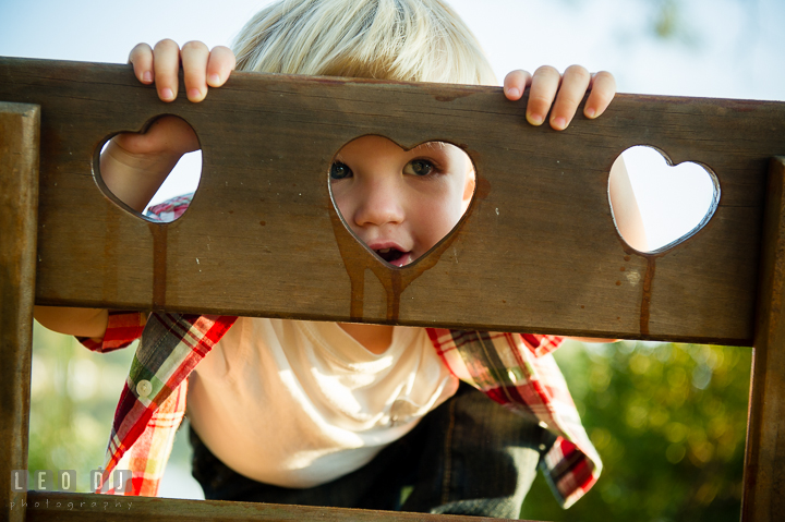 Little boy peeking through heart shaped opening. Queenstown, Eastern Shore Maryland candid children and family lifestyle portrait photo session by photographers of Leo Dj Photography. http://leodjphoto.com