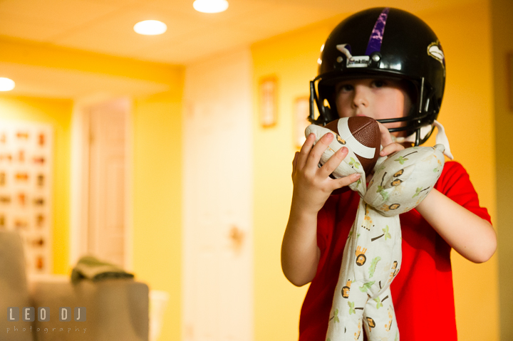 Toddler boy wearing helmet and playing footbal with his stuffed animal. Queenstown, Eastern Shore Maryland candid children and family lifestyle portrait photo session by photographers of Leo Dj Photography. http://leodjphoto.com