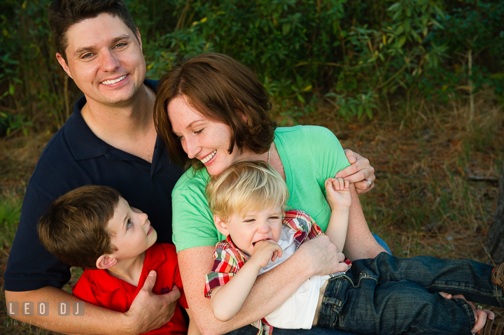 Father, Mother, and their sons hugging together. Queenstown, Eastern Shore Maryland candid children and family lifestyle portrait photo session by photographers of Leo Dj Photography. http://leodjphoto.com