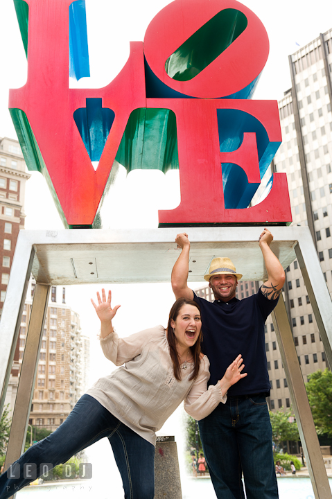 Engaged girl and her fiancé doing a goofy pose. Pre-wedding or engagement photo session at Phillies Ball Park, Love Park, Philadelphia, by wedding photographers of Leo Dj Photography.