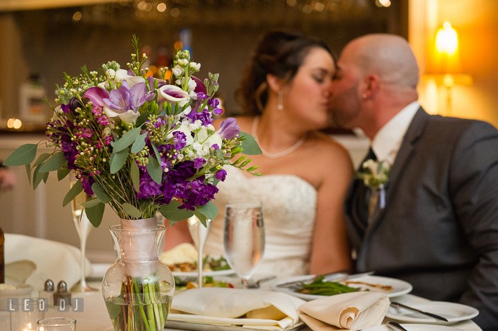 Bride's flower bouquet on sweet heart table. Bride and Groom kissing. The Tidewater Inn Wedding, Easton Maryland, reception photo coverage by wedding photographers of Leo Dj Photography. http://leodjphoto.com