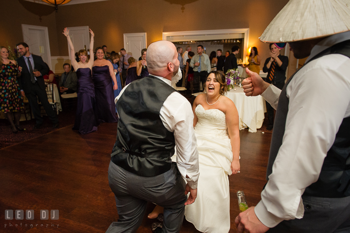 Bride laughing hard looking at Groom biting the garter. The Tidewater Inn Wedding, Easton Maryland, reception photo coverage by wedding photographers of Leo Dj Photography. http://leodjphoto.com