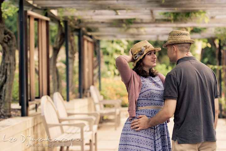 Engaged couple wearing hats smiling at each other. Pre-wedding engagement photo session at Brookside Gardens, Wheaton, Silver Spring, Maryland, by wedding photographer Leo Dj Photography.