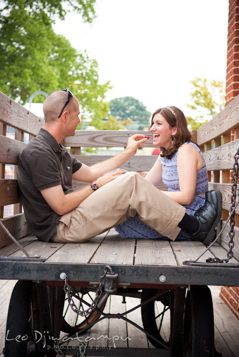 Engaged guy feeding his fiancée. Pre-wedding engagement photo session at Old Town Gaithersburg, Maryland, by wedding photographer Leo Dj Photography.