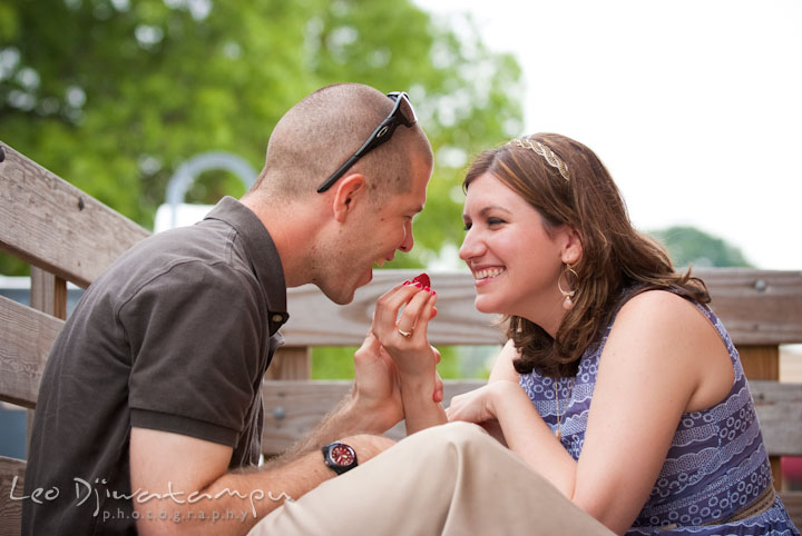 Engaged girl feeding her fiancé. Pre-wedding engagement photo session at Old Town Gaithersburg, Maryland, by wedding photographer Leo Dj Photography.