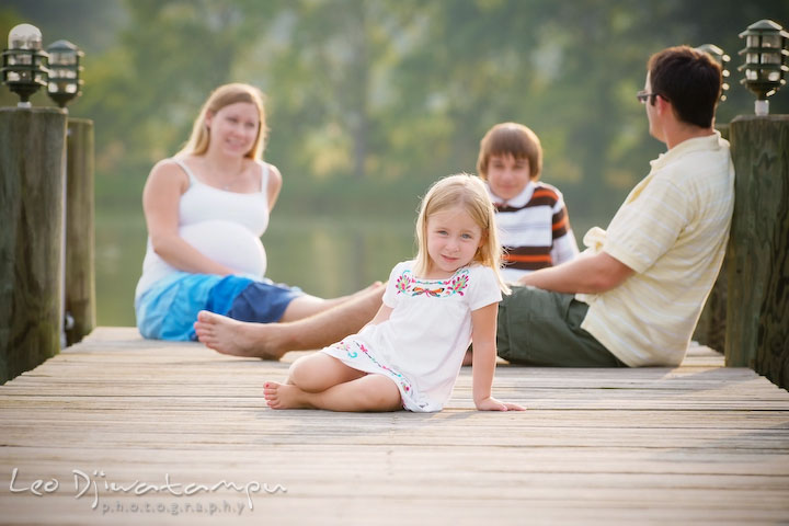 Little sister posing on the pier, family in the background, talking. Kent Island and Annapolis, Eastern Shore, Maryland Candid Family Maternity Session Photographer