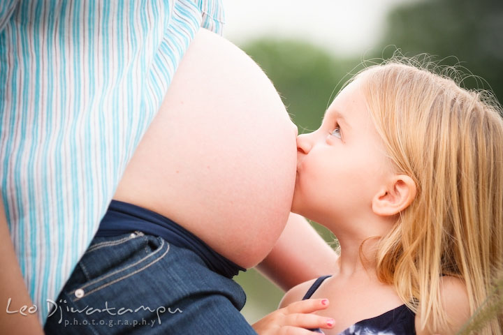 Daughter, little girl, kissing her pregnant mother's belly. Kent Island and Annapolis, Eastern Shore, Maryland Candid Family Maternity Session Photographer