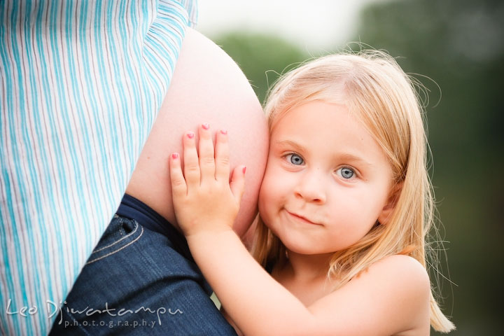 Daughter, little girl, trying to listen to the baby inside her pregnant mother's belly. Kent Island and Annapolis, Eastern Shore, Maryland Candid Family Maternity Session Photographer