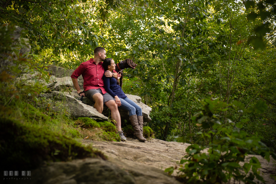 Rocks State Park Bel Air Maryland engaged couple cuddling accompanied with dog photo by Leo Dj Photography.