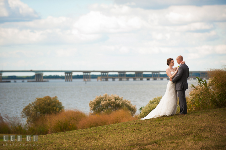 Bride and Groom embracing each other on a golf course hill with waterfront view. Hyatt Regency Chesapeake Bay wedding at Cambridge Maryland, by wedding photographers of Leo Dj Photography. http://leodjphoto.com