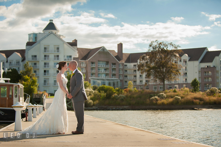 Bride and Groom holding hands on the dock with the hotel in the background. Hyatt Regency Chesapeake Bay wedding at Cambridge Maryland, by wedding photographers of Leo Dj Photography. http://leodjphoto.com