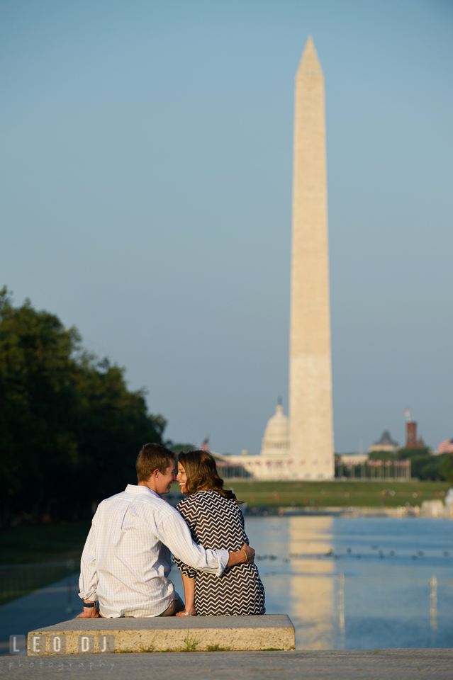 Engaged guy sitting close to his fiancée by the reflecting pool. Washington DC pre-wedding engagement photo session at Lincoln Memorial, by wedding photographers of Leo Dj Photography. http://leodjphoto.com