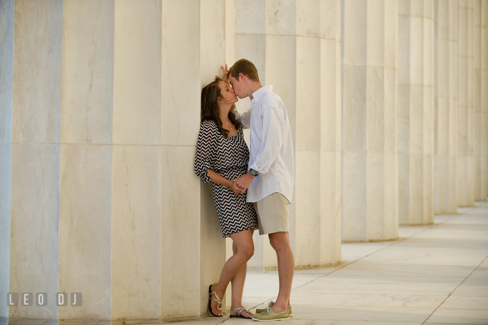 Engaged guy kissing his fiancée leaning by a large marble column. Washington DC pre-wedding engagement photo session at Lincoln Memorial, by wedding photographers of Leo Dj Photography. http://leodjphoto.com