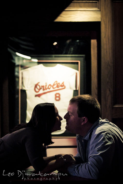 Engaged girl almost kissed her fiancé with Orioles jersey display in the background. Pre-wedding Engagement Photo Session Federal Hill Baltimore and Mother's Grille restaurant bar by wedding photographer Leo Dj Photography