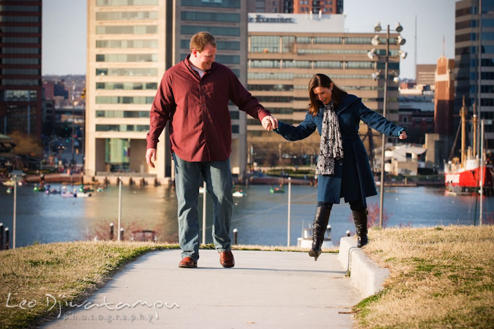 Engaged guy and girl walking, laughing with city view of high rise building. Pre-wedding Engagement Photo Session Federal Hill Baltimore and Mother's Grille restaurant bar by wedding photographer Leo Dj Photography